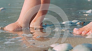 Mother and baby feet walking on sand beach. Newborn kid feet at beach