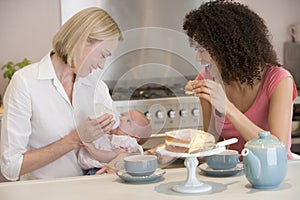 Mother and baby with friend eating cake