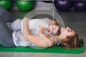 Mother and baby girl do exercises together in the gym