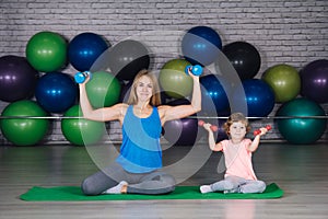 Mother and baby girl do exercises together in the gym