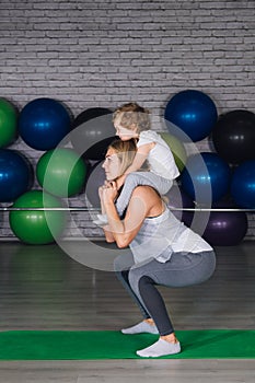 Mother and baby girl do exercises together in the gym