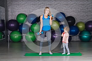 Mother and baby girl do exercises together in the gym