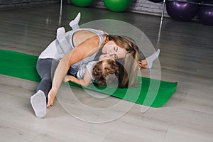 Mother and baby girl do exercises together in the gym