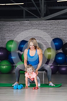 Mother and baby girl do exercises together in the gym