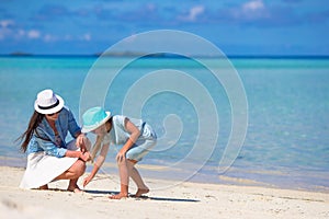 Mother and baby girl drawing on sandy beach