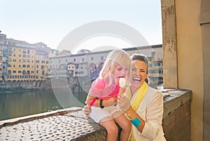 Mother and baby girl eating ice cream near ponte v