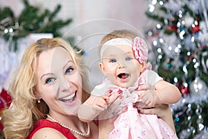Mother with baby girl in front of xmas tree. Christmas family portrait.
