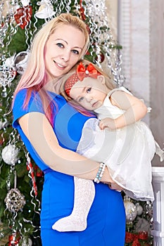 Mother with baby girl in front of xmas tree. Christmas family portrait.