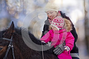 Mother and baby girl horseback riding