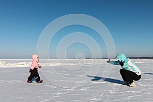 Mother and baby girl play on snow