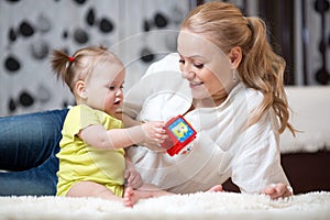 Mother and baby girl playing with developmental toys in living room photo