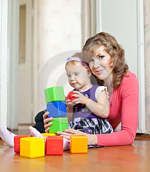 Mother and baby girl plays with blocks in home