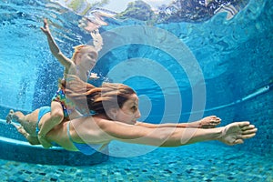 Mother, baby girl swim and dive underwater in pool