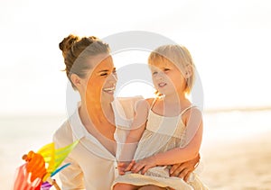 Mother and baby girl with windmill toy on beach