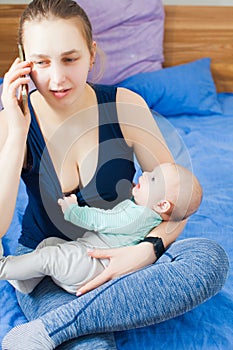 Mother with baby in her arms talking on phone