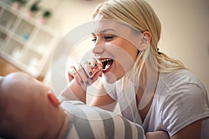 Mother with baby at home holding her hand an laughing.