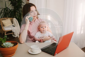 Mother and baby in home office with laptop and telephone