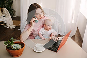 Mother and baby in home office with laptop and telephone