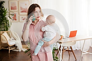 Mother and baby in home office with laptop and telephone