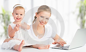 Mother and baby at home using laptop computer