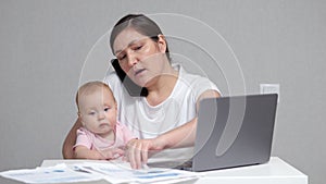 Mother with baby on lap talks on phone analysing report