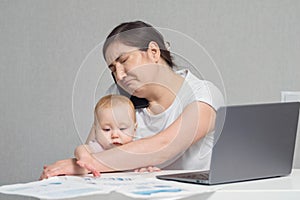 Mother with baby on lap talks on phone analysing report