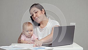 Mother with baby on lap talks on phone analysing report