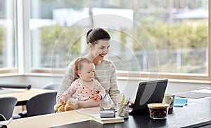 Mother with baby and laptop working at home office