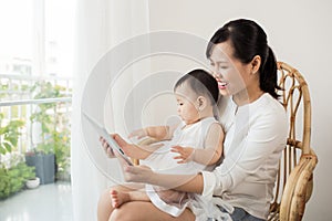 Mother and baby are looking to play and read tablet computer at