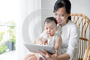 Mother and baby are looking to play and read tablet computer at