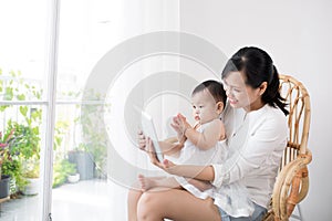 Mother and baby are looking to play and read tablet computer at