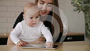 Mother and baby are looking to play and read tablet computer on the couch at home