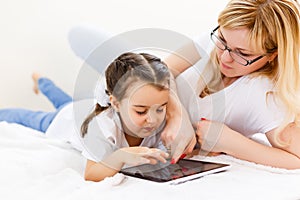 Mother and baby are looking to play and read tablet computer on the couch at home