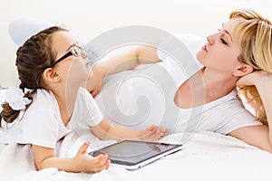 Mother and baby are looking to play and read tablet computer on the couch at home