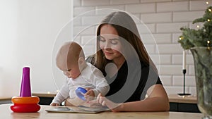 Mother and baby are looking to play tablet computer on the couch at home