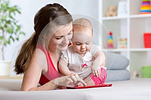 Mother and baby are looking to play tablet computer on the couch at home