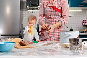 Mother and baby make gingerbread together. Mother& x27;s Day concept and cooking festive home-cooked meals with children