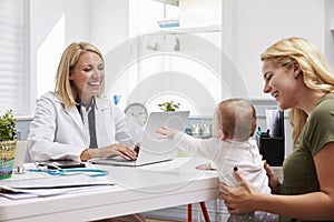 Mother And Baby Meeting With Female Doctor In Office