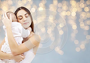 Mother with baby over festive lights background