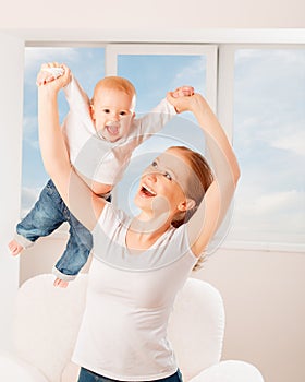 Mother and baby are playing active games, do gymnastics and laughing at home