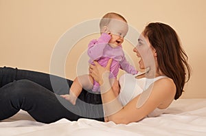 Mother with baby playing in bed