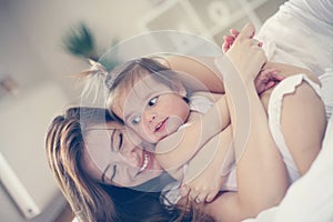 Mother and baby playing in the bed.