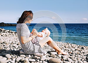 Mother and baby playing outdoors on sea beach.