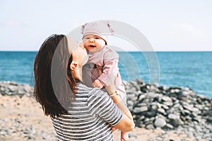 Mother and baby playing outdoors on sea beach.