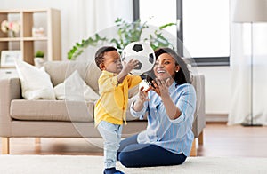 Mother and baby playing with soccer ball at home