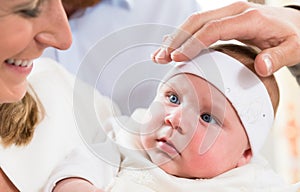 Mother, baby and priests hand at christening