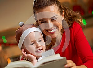 Mother and baby reading book in christmas decorated kitchen
