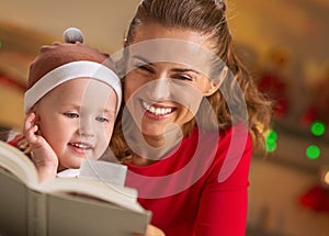 Mother and baby reading book in christmas decorated kitchen