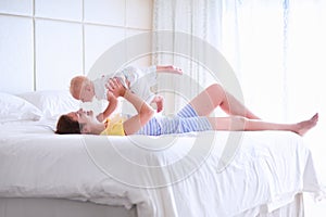 Mother and baby relaxing in white bedroom
