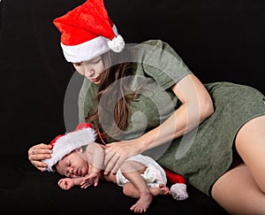 Mother and baby in santa red dress smile on a darck background